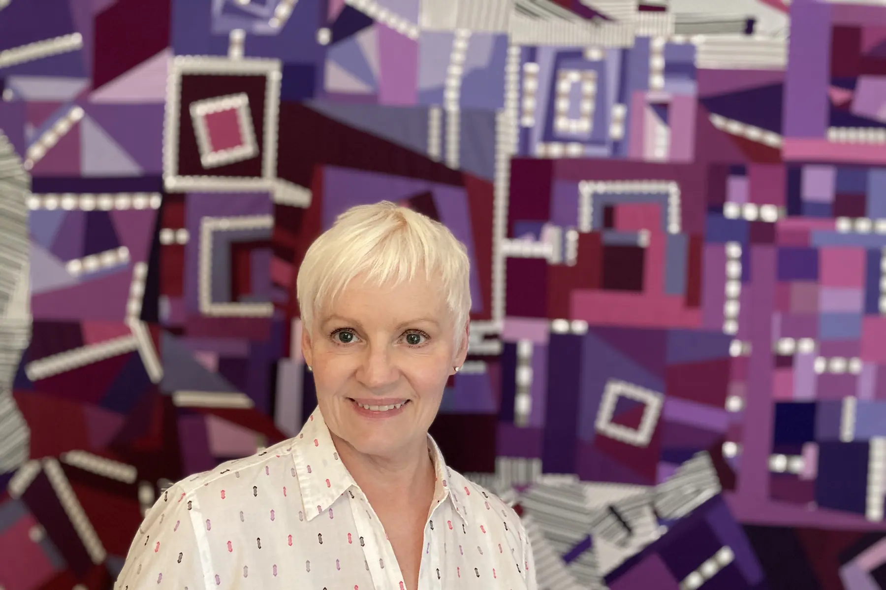 Jo Allbutt standing with one of her art quilts