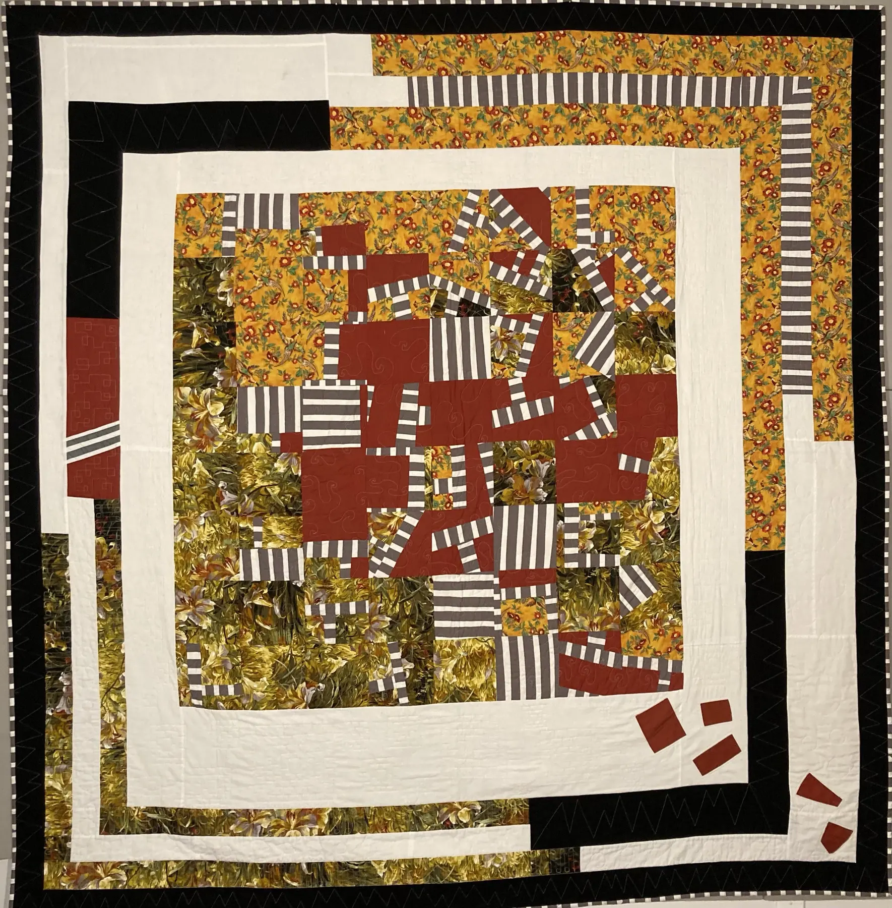 Large art quilt with nested cream and black borders surrounding an improvised ochre and burgundy centre