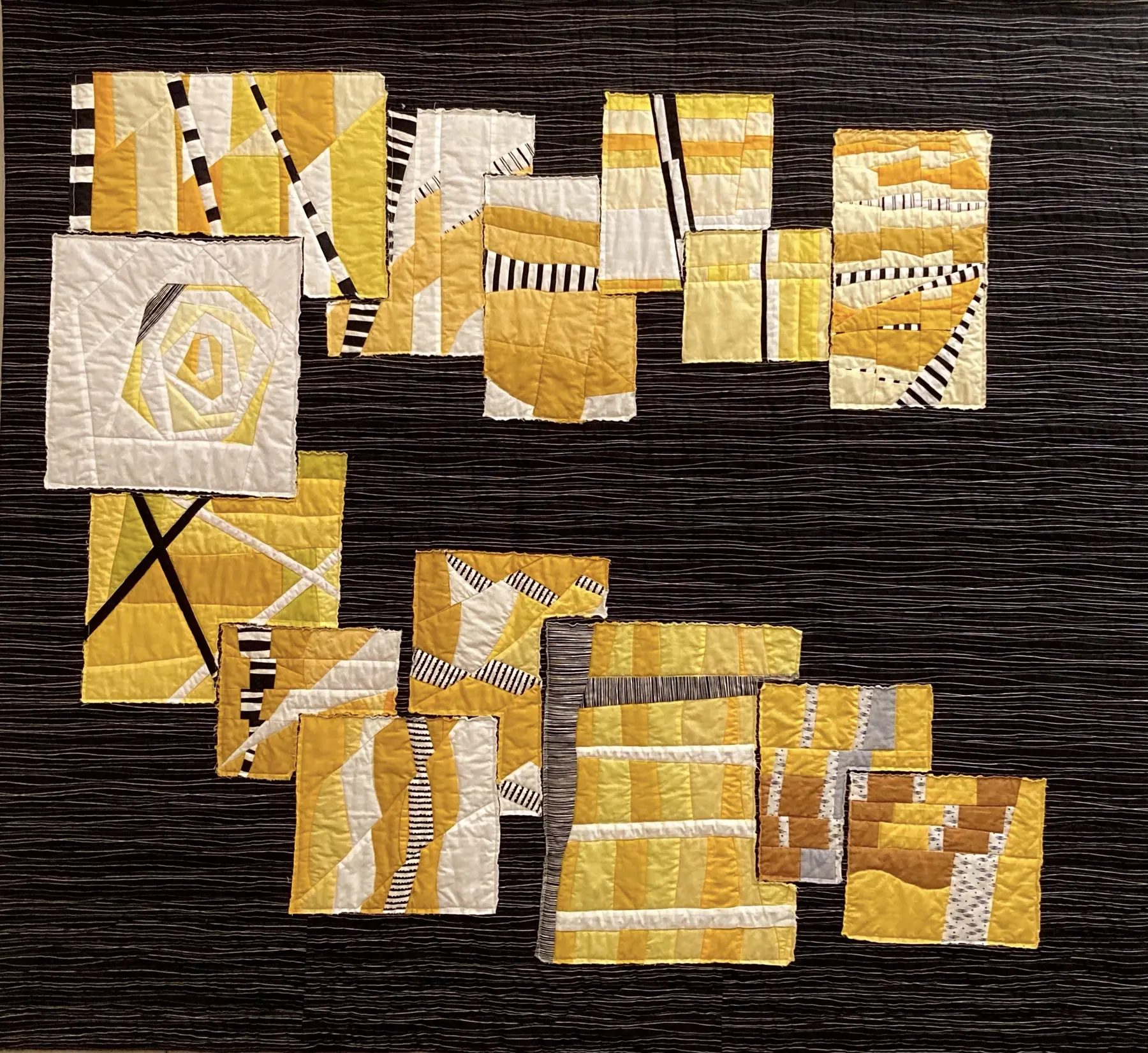 Art quilt with fragmented yellow and white blocks arranged in a C shape on black