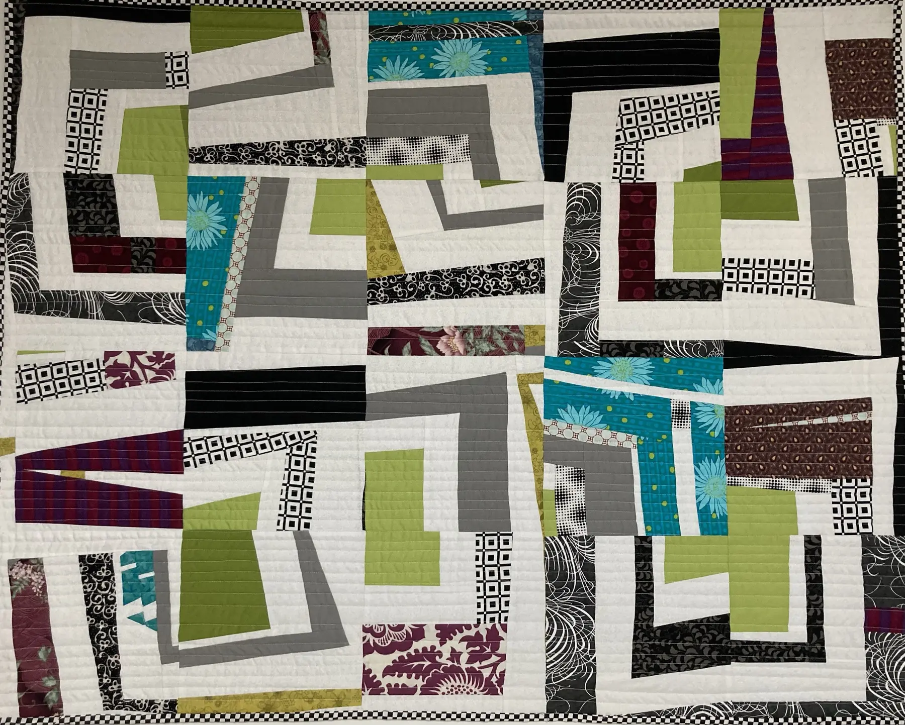 Abstract art quilt with angular black, grey, green and turquoise shapes on a pale ground
