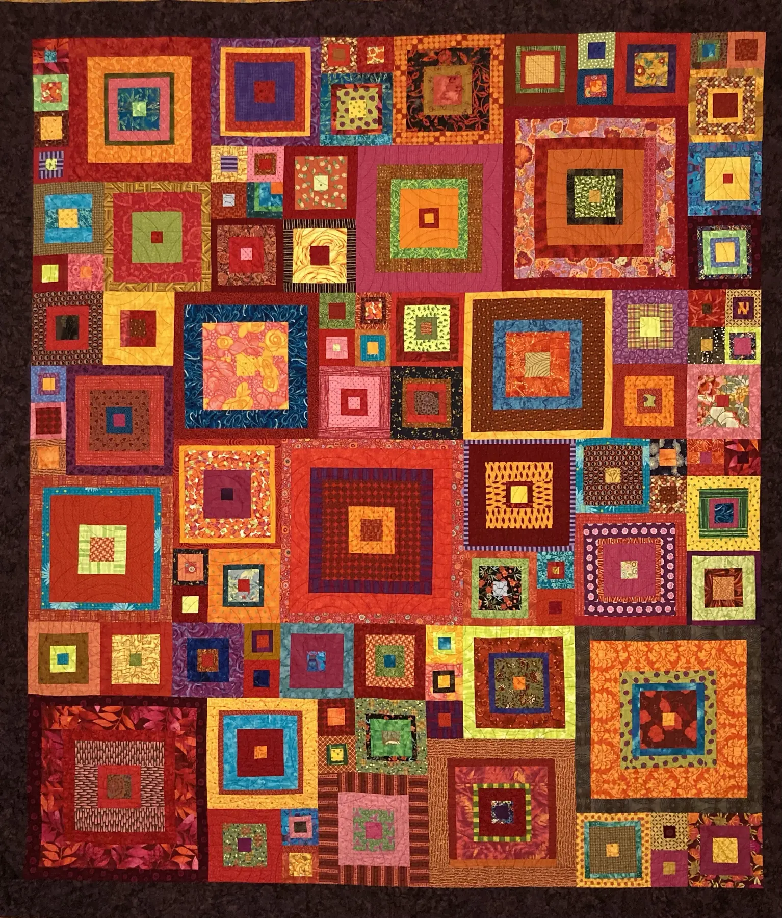 Colourful art quilt made of many nested rectangular blocks on a warm patterned ground