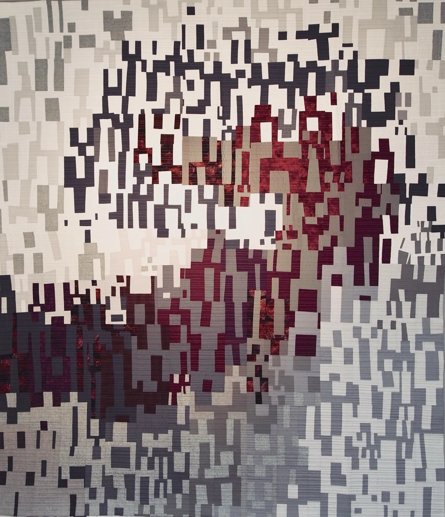 Art quilt with a pixelated white, grey and burgundy yin-yang composition